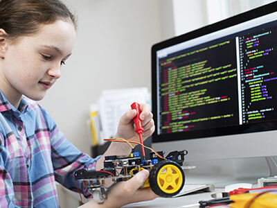 Schülerin programmiert Roboter vor Computer