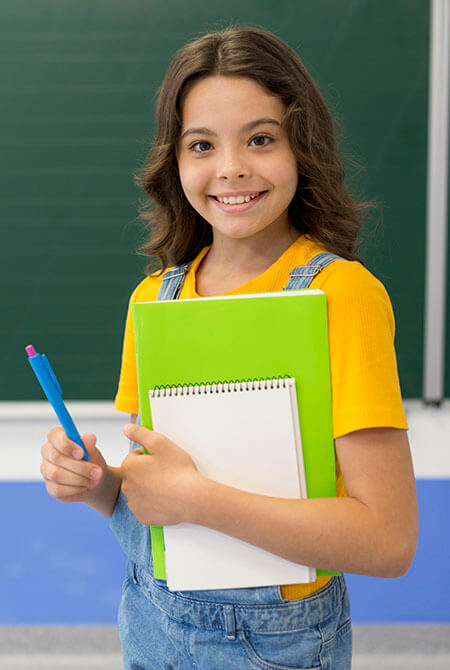Glückliche Schülerin steht vor einer Tafel